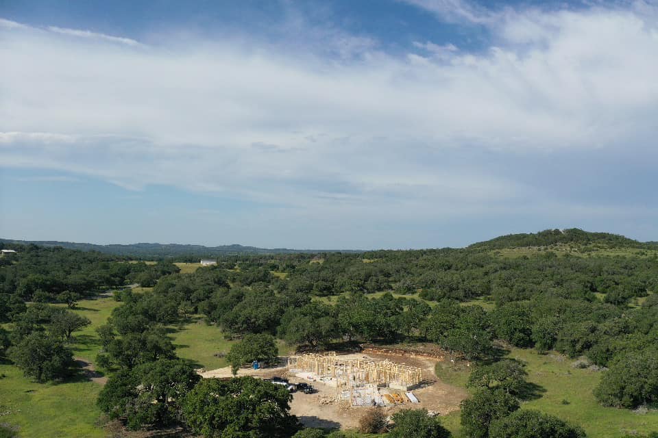 Aerial view of new construction site surrounded by Hill Country oaks